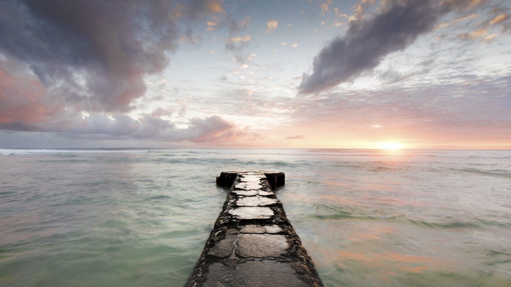 Cement pier extending towards the horizon on a cloudy sunset, Big Island, Hawaii