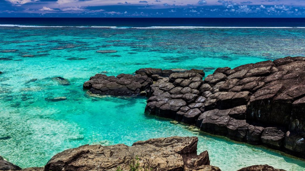Tropical beach surrounded by black rocks, Rarotonga, Cook Islands