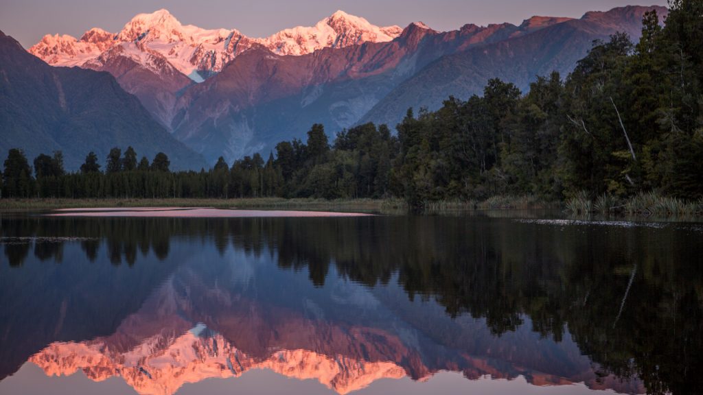 Snowcapped mountains Cook and Fox reflected in lake Matheson at sunset, Westland, New Zealand South Island