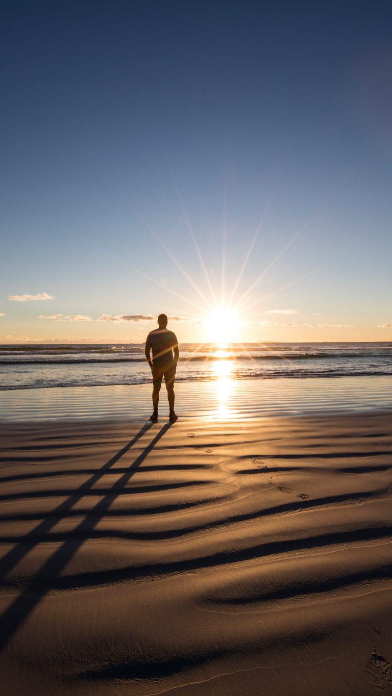 Man standing on beach looking at the sunset, Western Australia ...