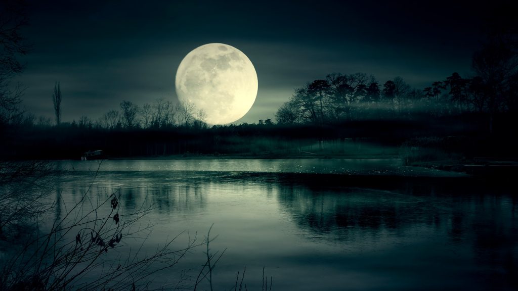 Spooky moonrise over lake, super moon at night