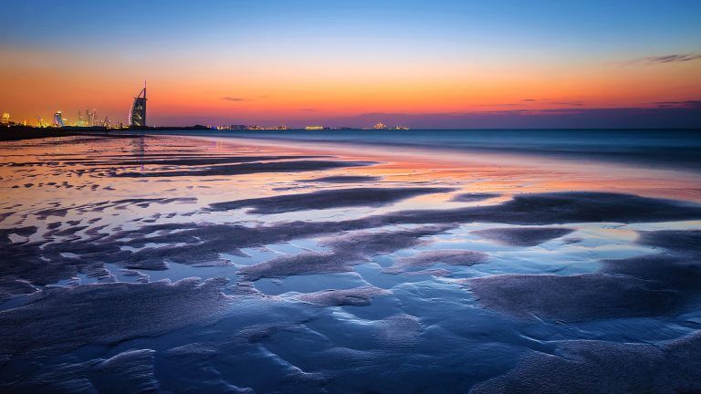 Beautiful Dubai beach in sunset light with view on a luxury modern city ...