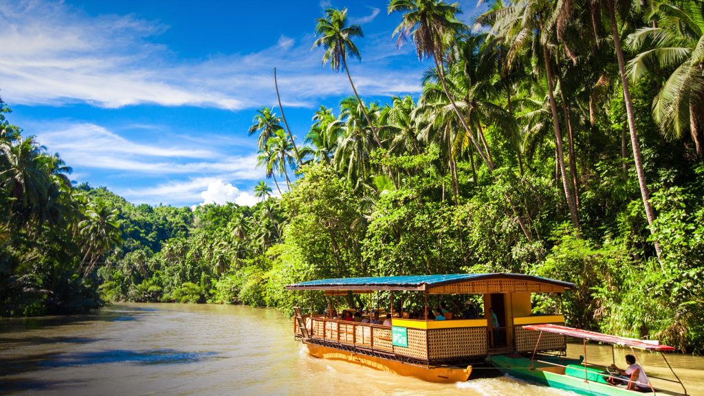 Exotic cruise boat with tourists on a jungle river Loboc, Bohol island, Philippines