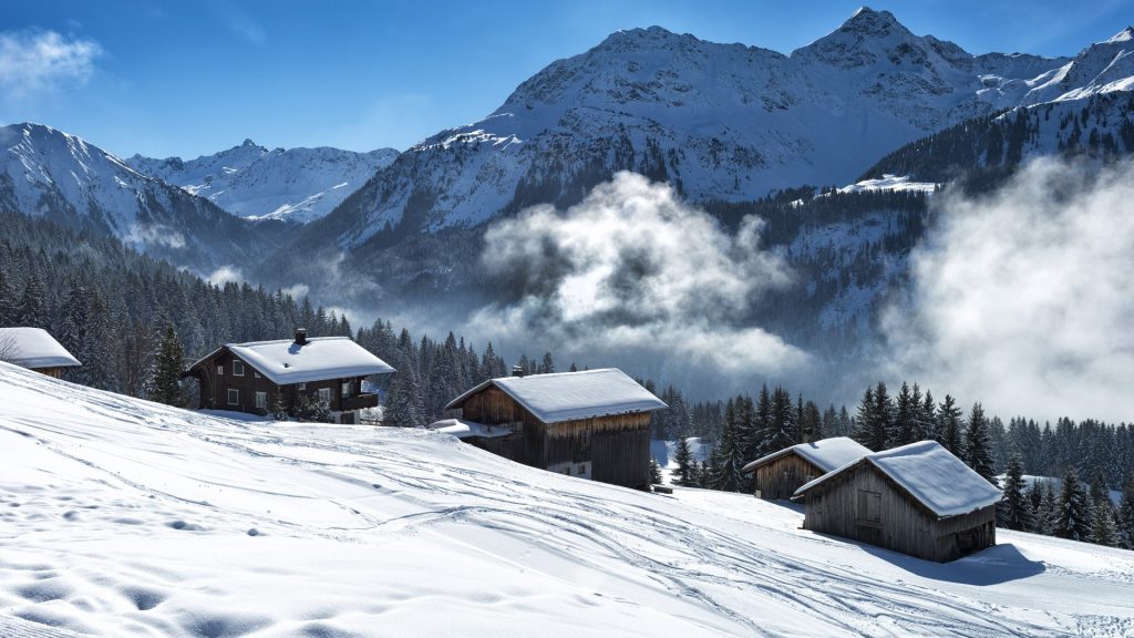 Winter landscape with ski lodges beside the ski slope and the forest, Vorarlberg, Austria