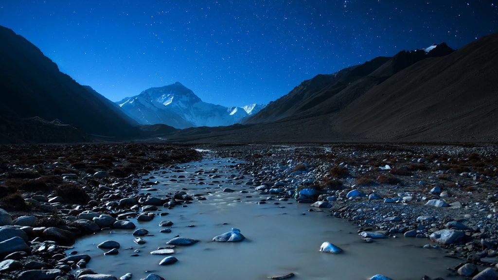 Pebbles in river in valley under stars at night, Everest, Tibet, China