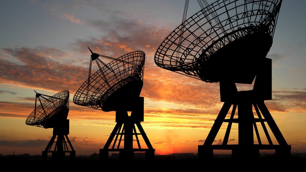 Three satellite dishes over sunset