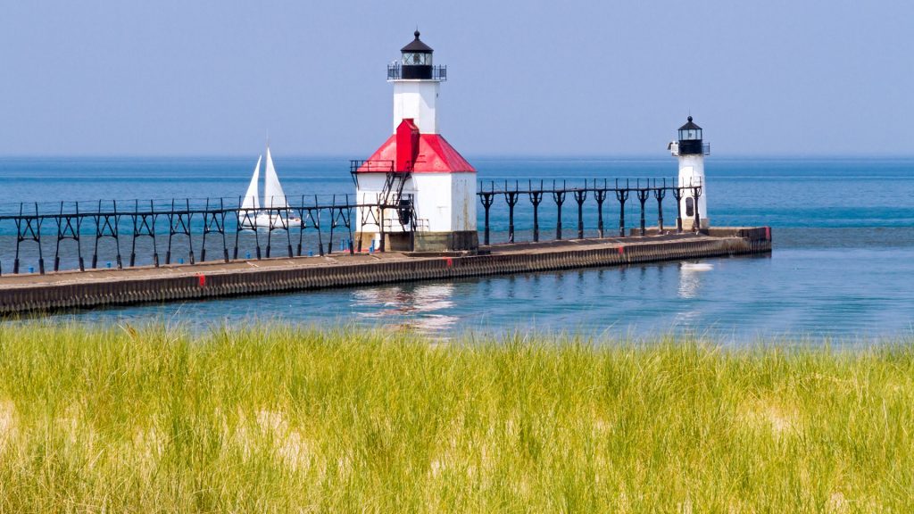 North pier lighthouses with a sailboat on Lake Michigan, St. Joseph, Michigan, USA
