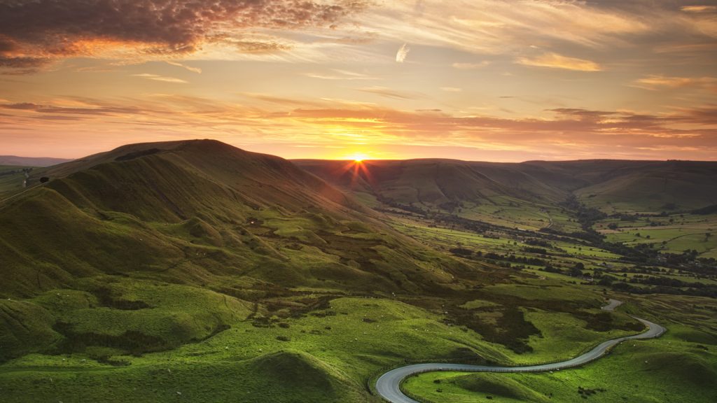 Sunset over a winding road beneath Mam Tor, Peak District in late summer, England, UK