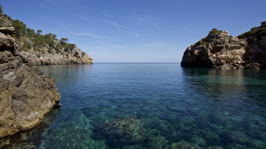 Clear water and beach cafe on rocky promontory, Deia bay, Mallorca, Spain's Balearic Islands