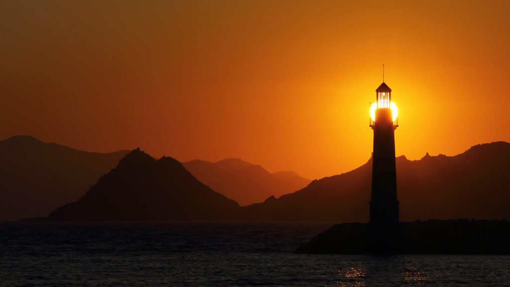 Seascape at sunset with lighthouse on the coast, seaside town of Turgutreis, Turkey