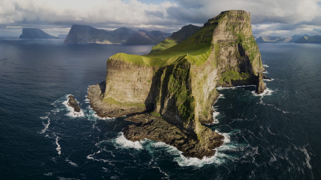 View of cliffs above the ocean and Kallur lighthouse, Kalsoy island, Faroe Islands, Denmark