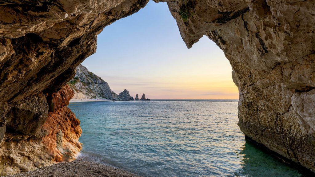 View from a cave at Two Sisters beach (Le due sorelle) at sunrise, Conero, Italy
