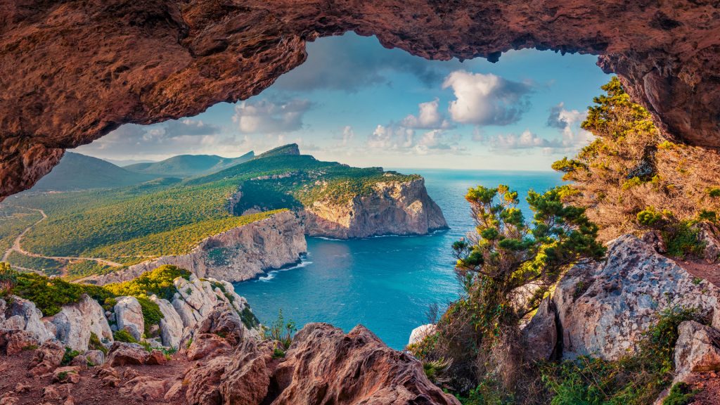 Summer view of Caccia cape from the small cave in the cliff, Sardinia island, Italy