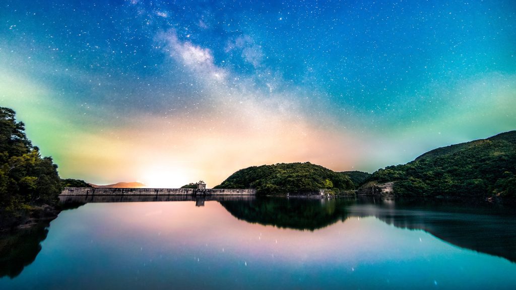 Milky way over the calm Tai Tam Park reservoir at night, Hong Kong