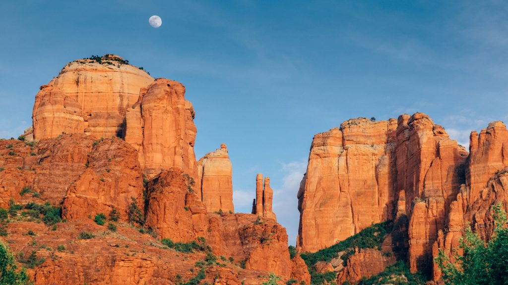 The late afternoon sun lights up Cathedral Rock with the full Moon in Sedona, Arizona, USA