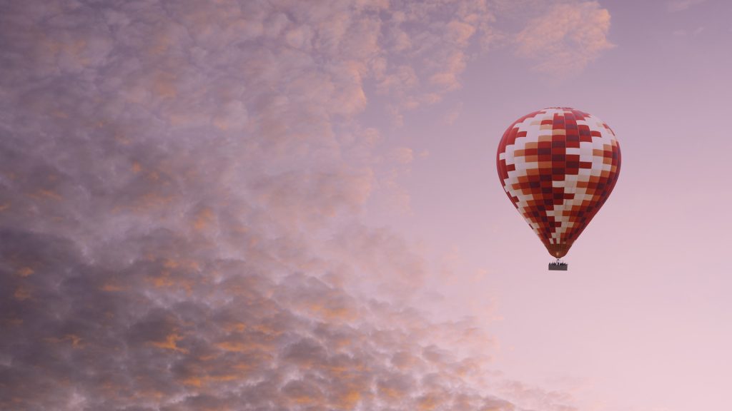 Composition of vibrant hot air balloon flying in pink cloudy sky, Cappadocia, Turkey