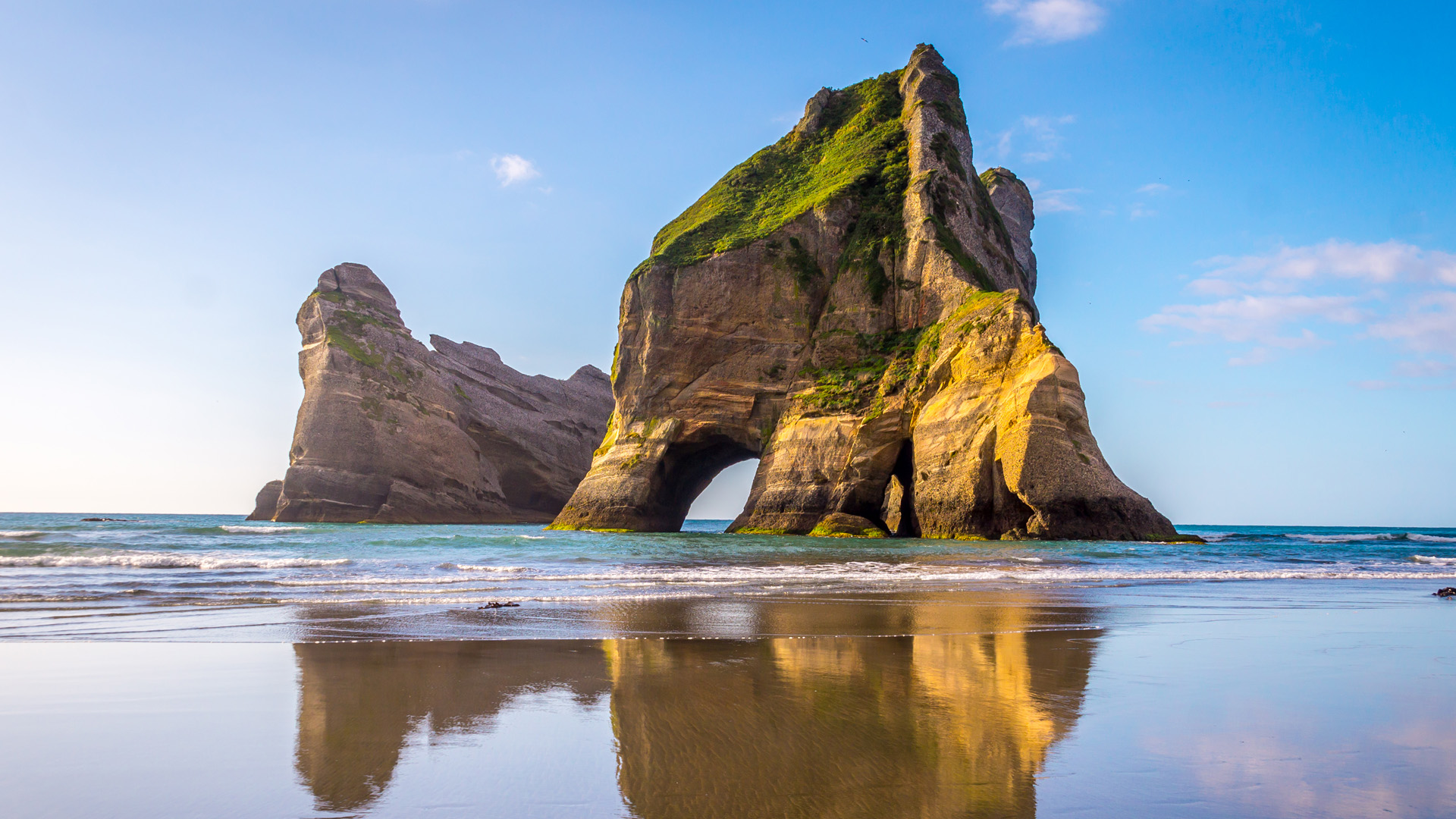 Rock Formations reflect in the water, Wharariki Beach, South Island of ...