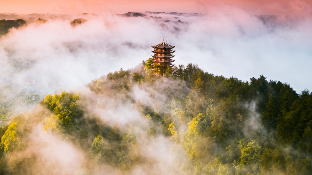 Aerial view of a buddhist temple on hilltop during a foggy day at sunset, China