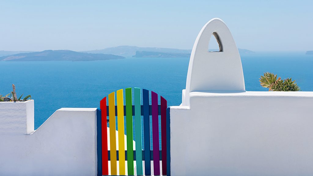 Facade of brick fence or white wall with a rainbow gate, Santorini or Thira island, Greece