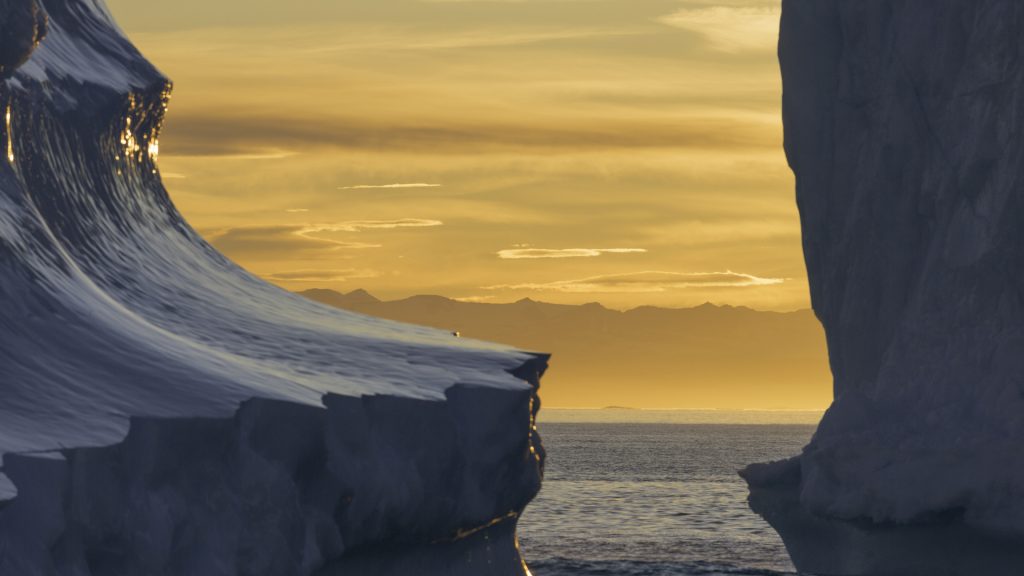 Dramatic light hitting a pair of icebergs at sunset, Scoresby Sound, Greenland