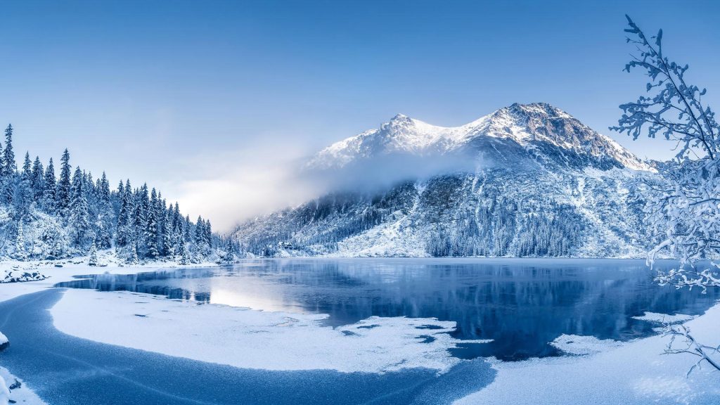 Winter panoramic landscape with frozen mountain lake and clear blue sky, Alps, Switzerland