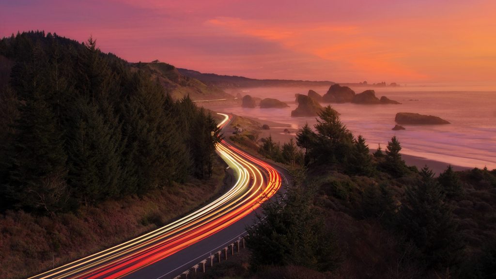Light trails along a road curve at coast during sunset, Pistol River State Park, Oregon, USA