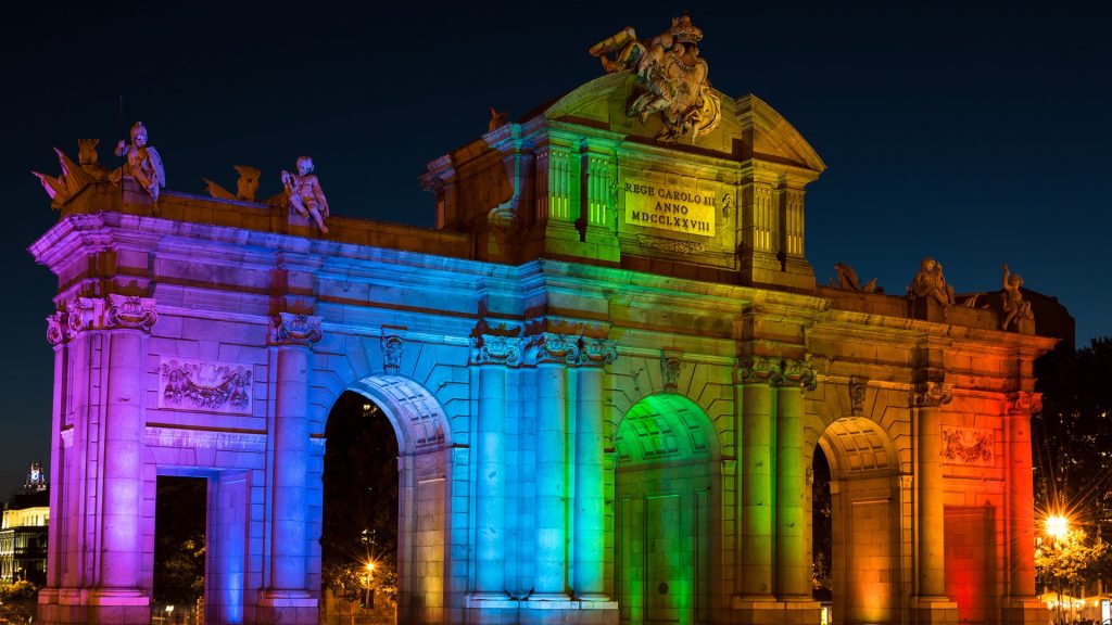 Alcala Gate (Puerta de Alcalá) illuminated in rainbow colours, Madrid, Spain