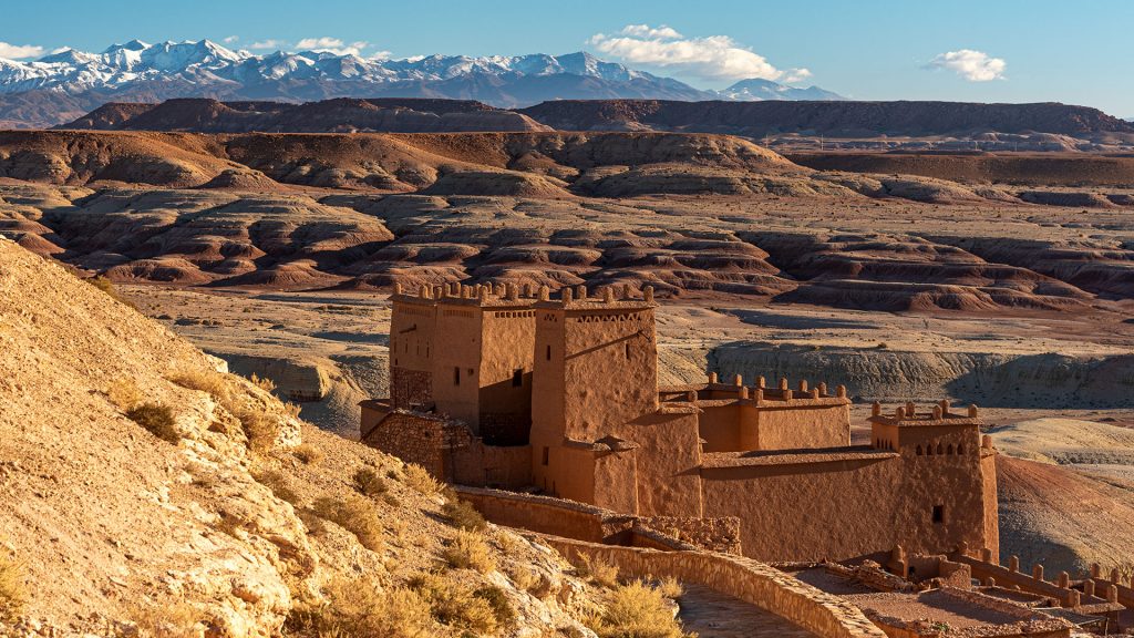 Ait Benhaddou in warm morning light with huge mountains in the background, Morocco