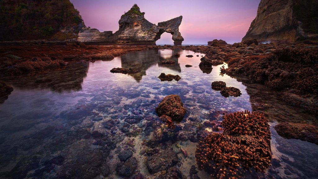 Atuh beach after sunset, coral reef in low tide, arch and pinnacle, Nusa Penida, Indonesia