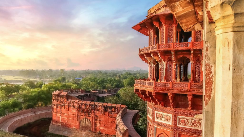 Agra Fort made of red sandstone and marble with view of cityscape at sunrise, India